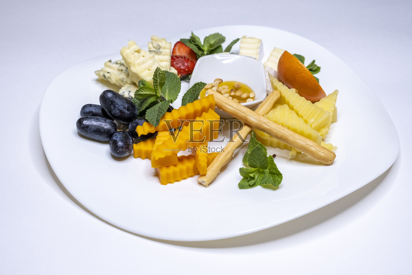 奶酪盘:埃曼塔尔奶酪、卡门贝尔奶酪、蓝纹奶酪、面包条、核桃、榛子、蜂蜜、葡萄。白色背景。副本的空间。餐厅菜单。葡萄酒小吃照片摄影图片