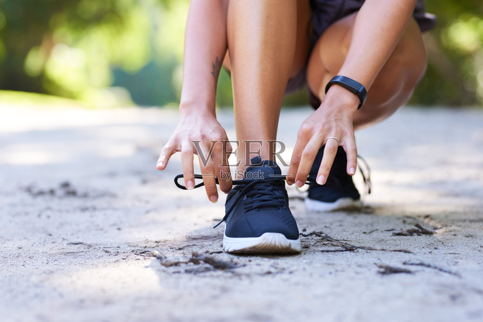 年轻女子在公园越野跑前系鞋带的剪影照片摄影图片