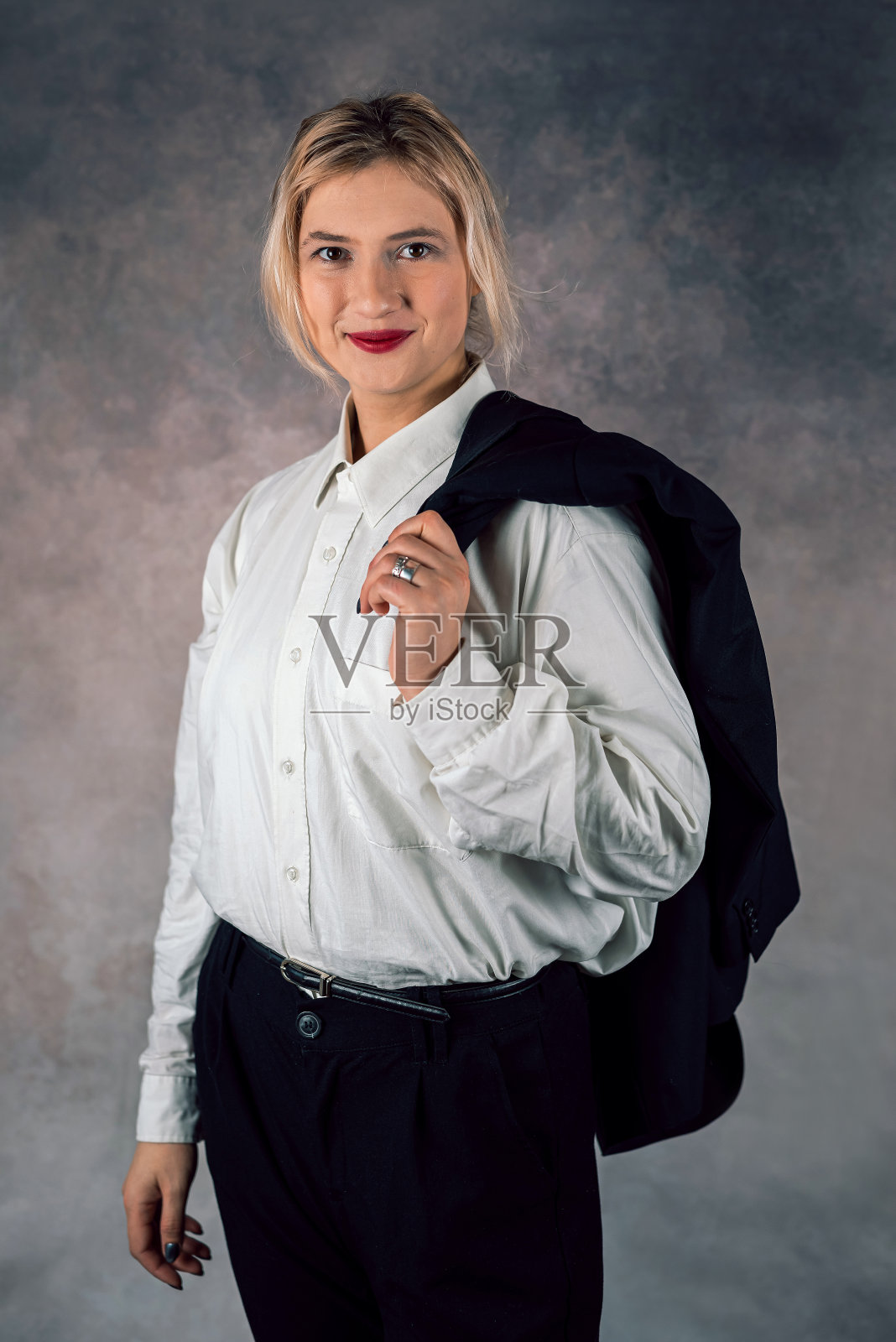 年轻的女商人站在一个孤立的单色摄影棚背景上对着镜头微笑照片摄影图片