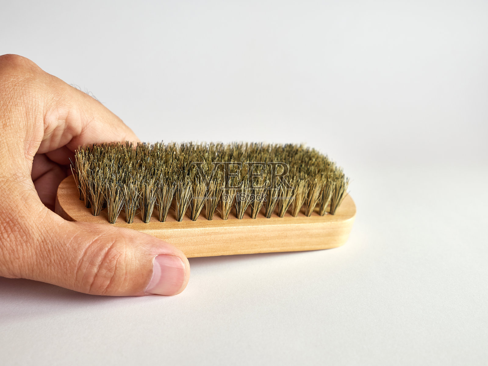 一个男人手里拿着画笔，背景是白色的。照片摄影图片