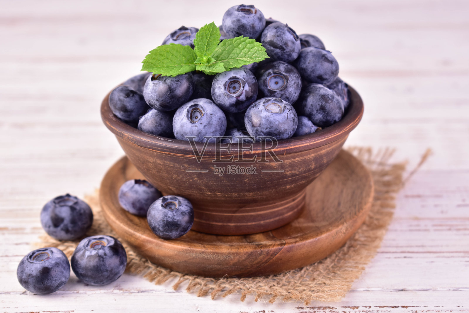 蓝莓在白色木制背景上的粘土碗里。特写镜头。照片摄影图片