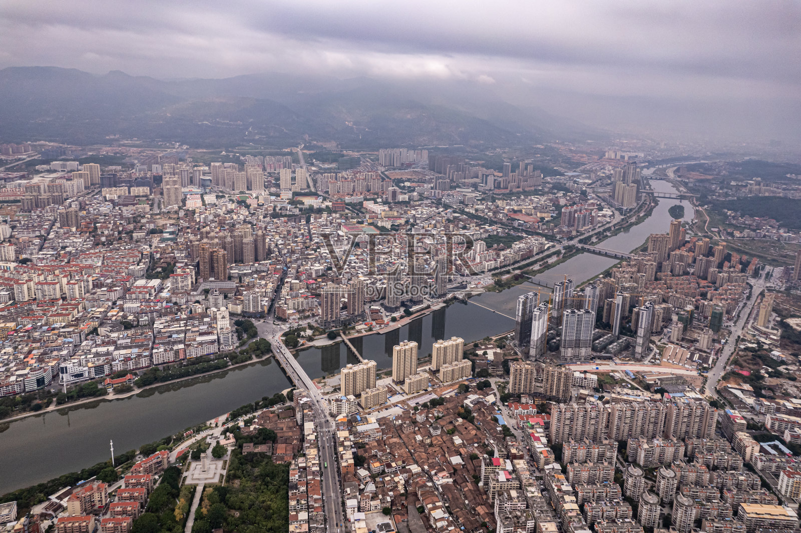 多云城市中人口稠密的建筑物和河流的鸟瞰图照片摄影图片