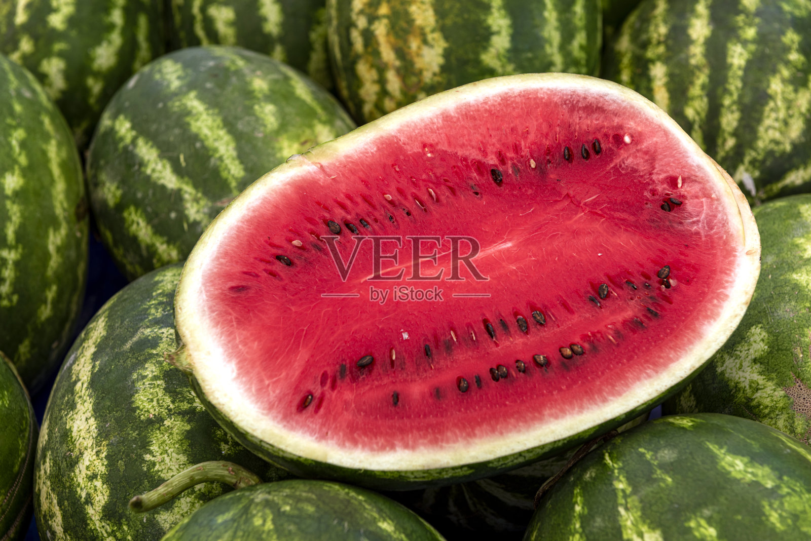 半切的黑籽西瓜放在一堆西瓜上照片摄影图片