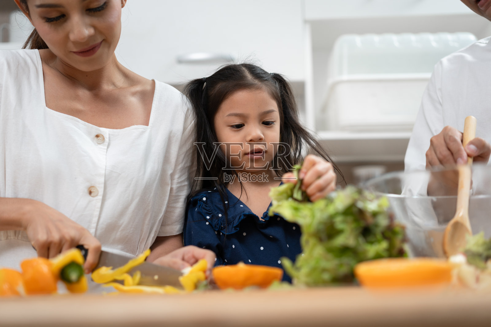 亚洲女孩在家里的厨房里和家人一起做沙拉照片摄影图片