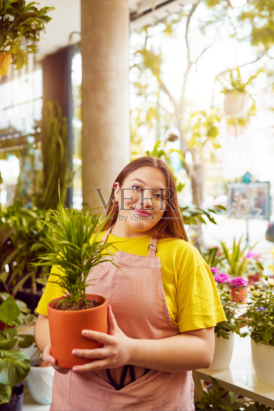 肖像白人身材较大的女售货员在植物店内部拿着一盆植物照片摄影图片