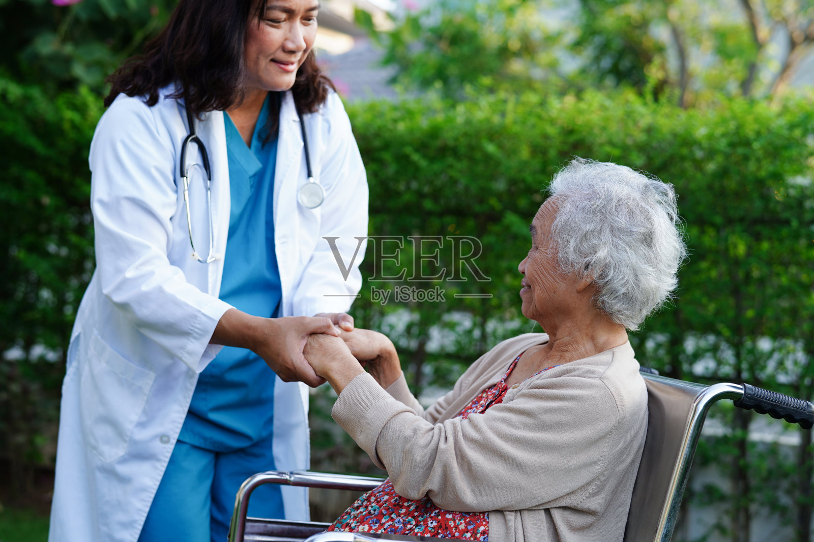 医生在公园帮助坐在轮椅上的亚洲残疾老年妇女，医疗概念。照片摄影图片