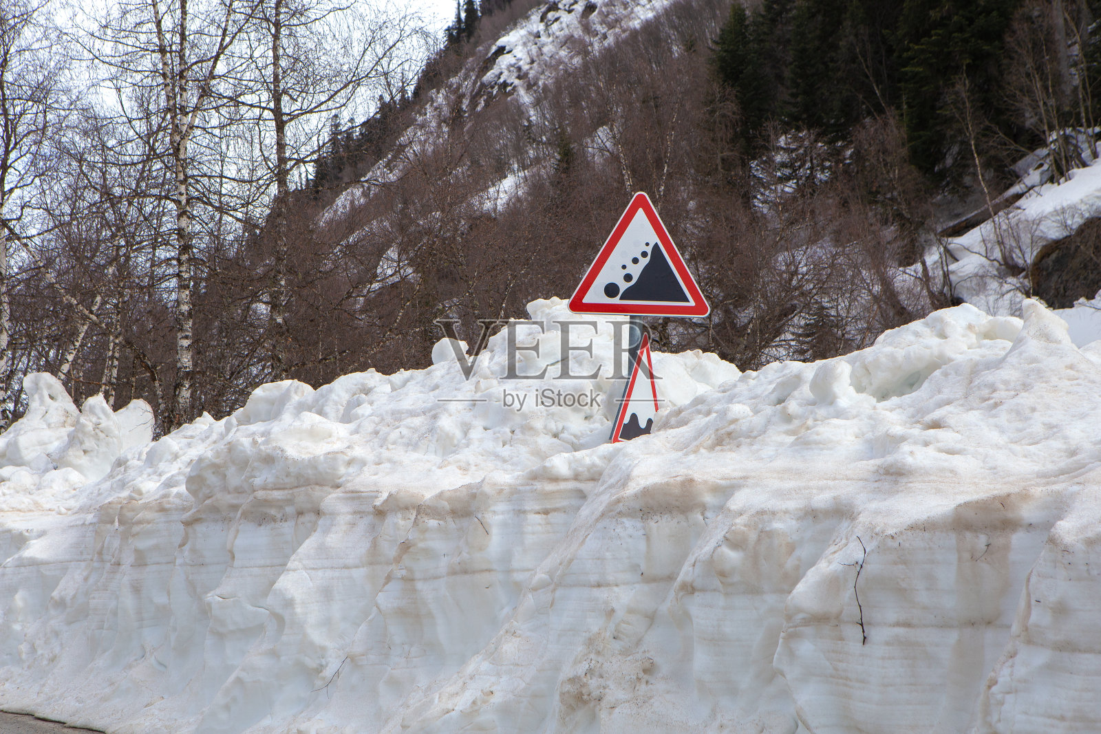 一条沥青路，冬天后雪很多，还有一个“雪崩”路标照片摄影图片