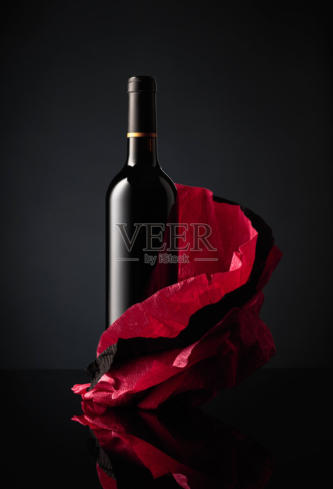 一瓶红酒放在皱巴巴的纸上。照片摄影图片