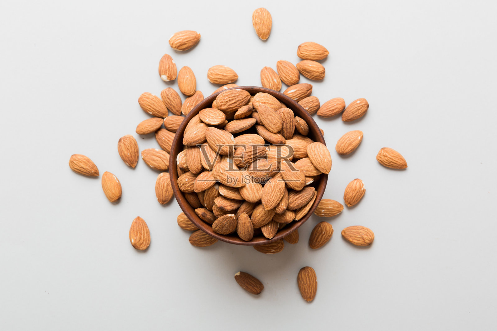 新鲜健康的杏仁碗在彩色的桌子背景。俯视图照片摄影图片