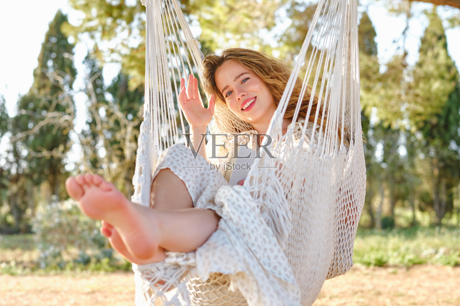 快乐的女人拿着书在大自然的吊床上摇摆照片摄影图片