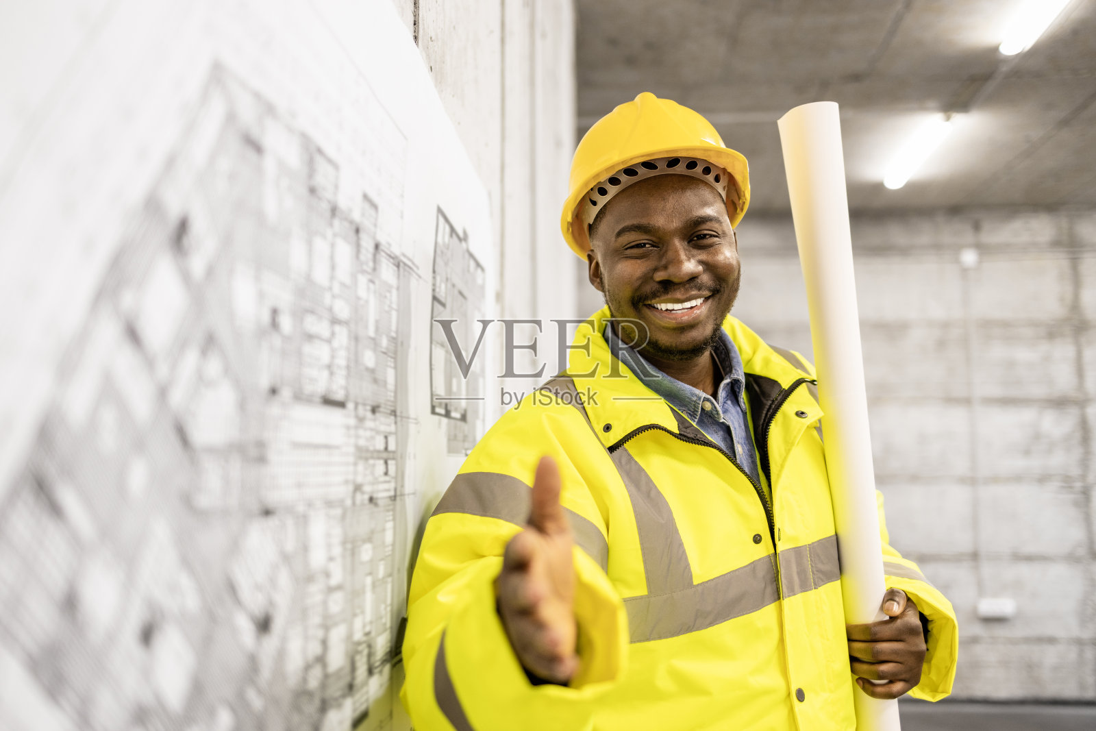 建筑工人的工作和职业。在建筑工地，穿着防护装备的工程师手持蓝图的肖像。照片摄影图片