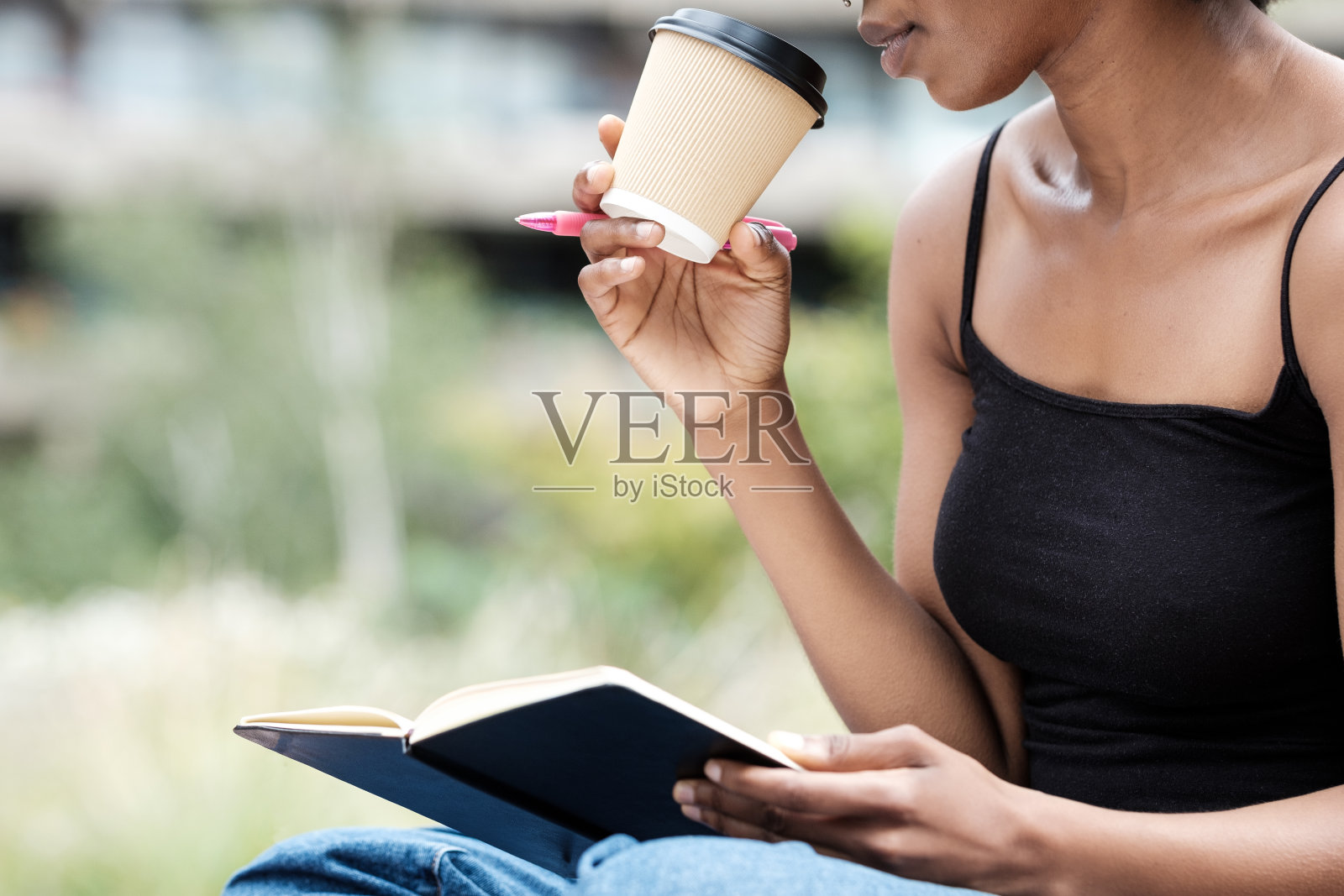 不认识的女人拿着笔记本，笔和咖啡。照片摄影图片