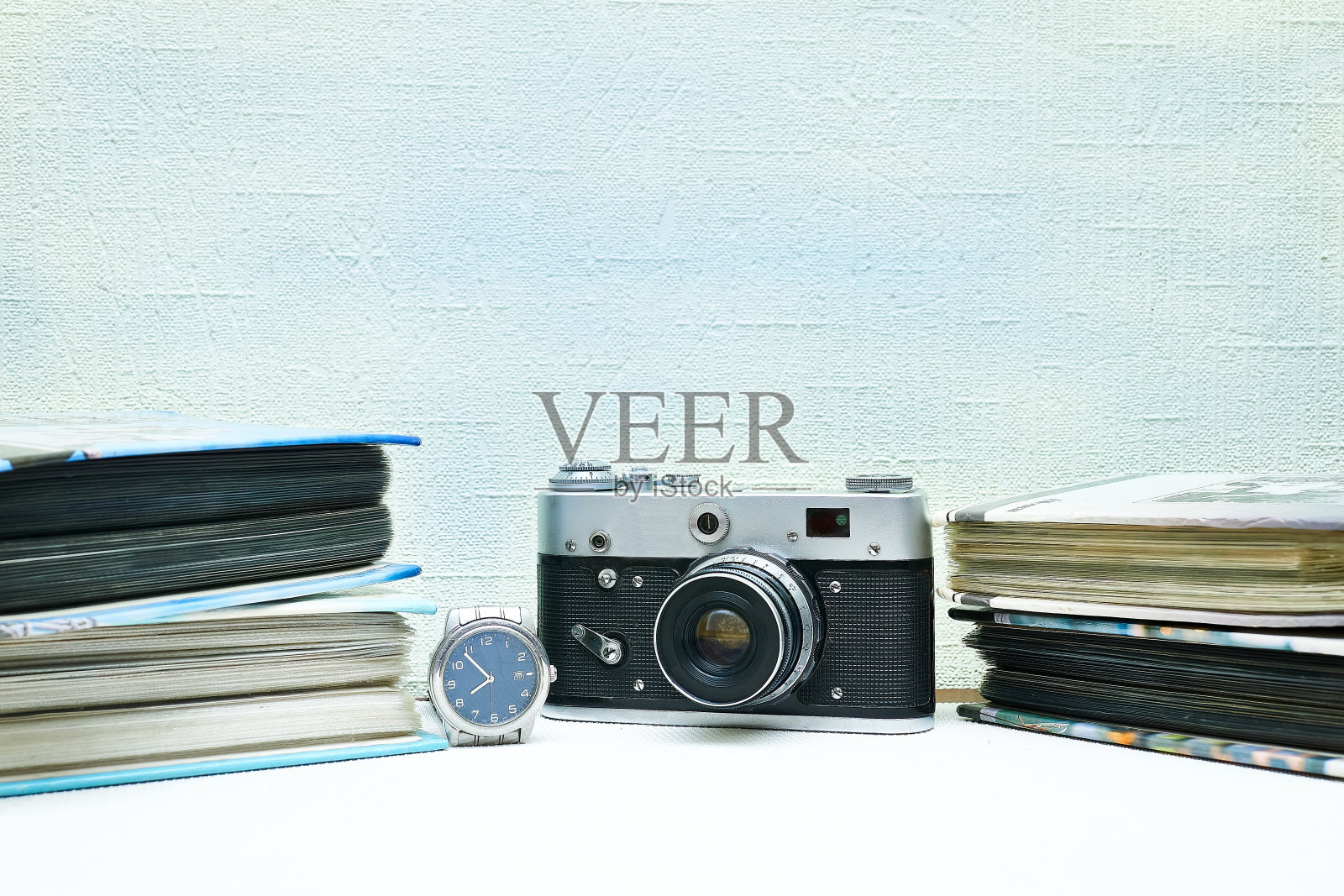 旧的老式胶片照相机与相册和手表孤立在淡粉色照片摄影图片