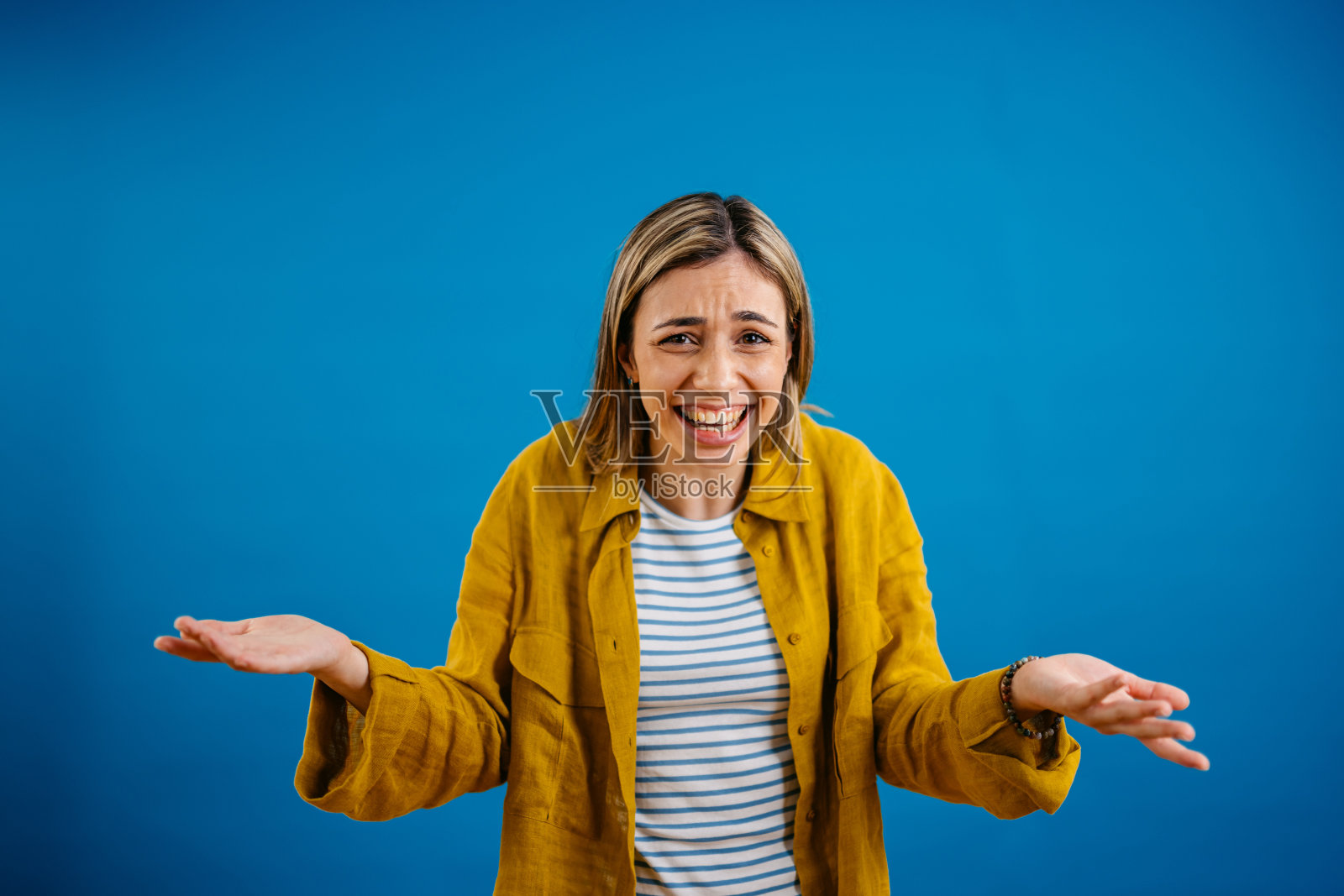 站在蓝色背景下的年轻女子耸耸肩照片摄影图片