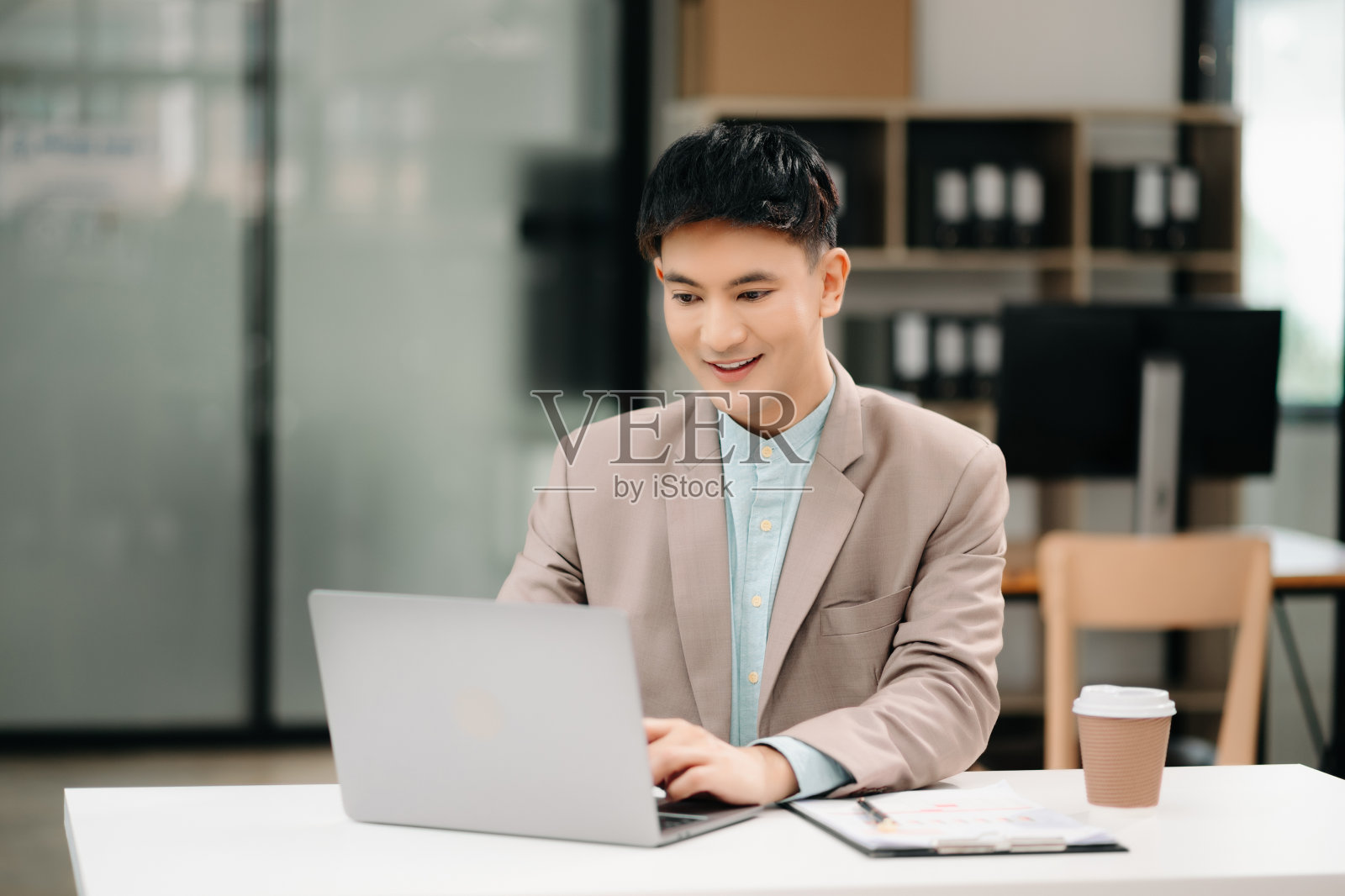 年轻的亚洲商人在办公室用笔记本电脑、平板电脑和在纸上做笔记。照片摄影图片