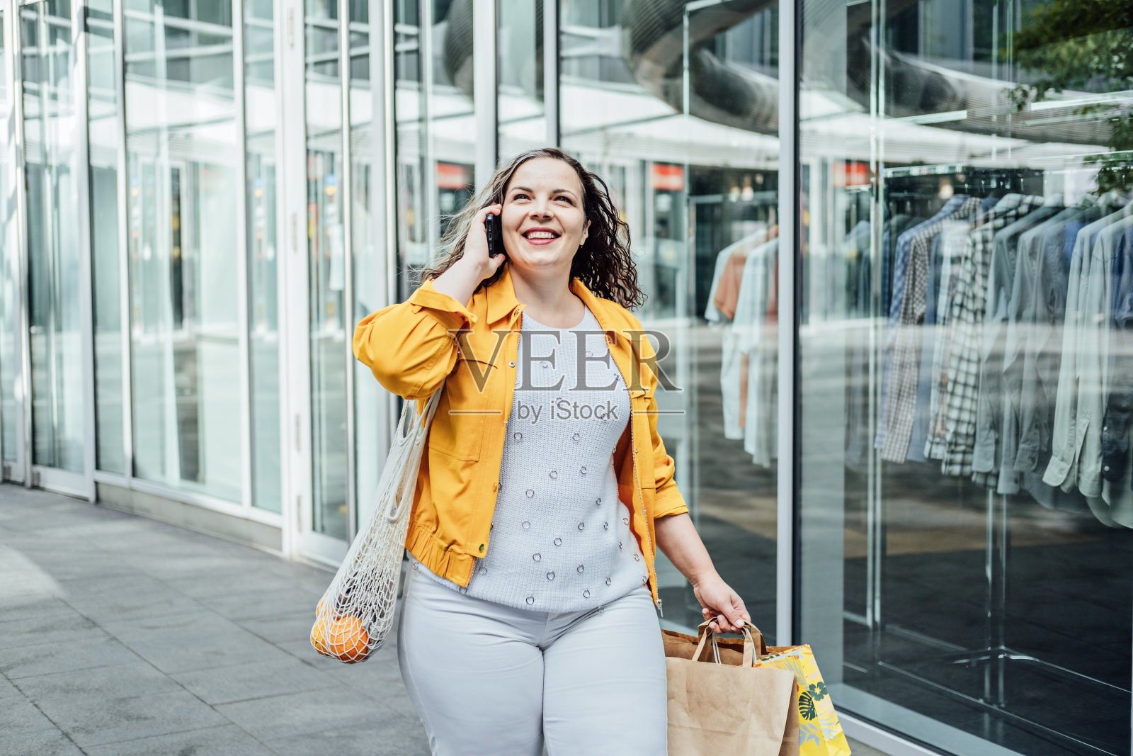 如何为大肚子打造一个加码胶囊衣橱。造型基本胶囊衣橱服装。户外肖像的时尚曲线的女人在购物照片摄影图片