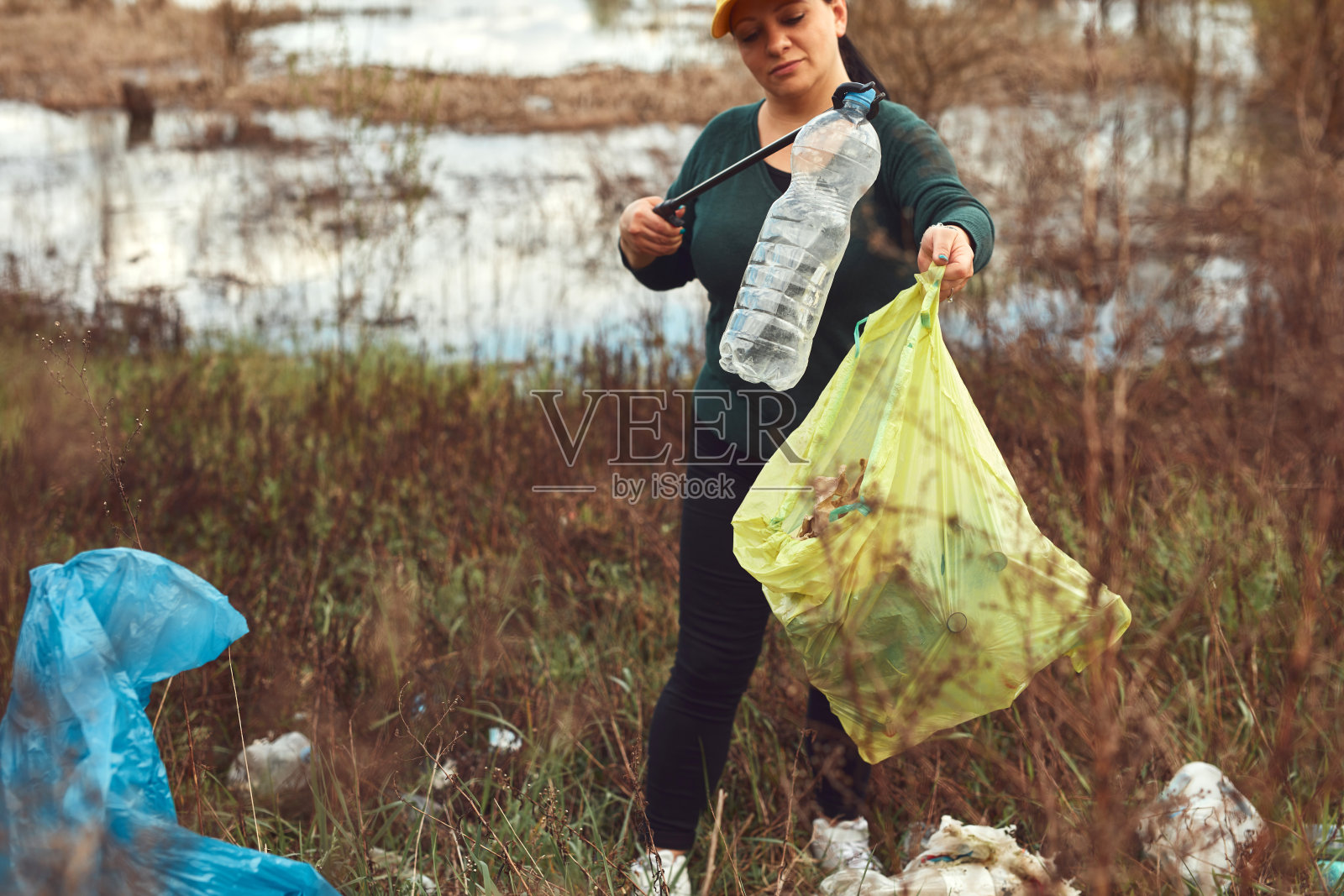 志愿者和环保人士正在清理堆满垃圾的脏湖岸。照片摄影图片