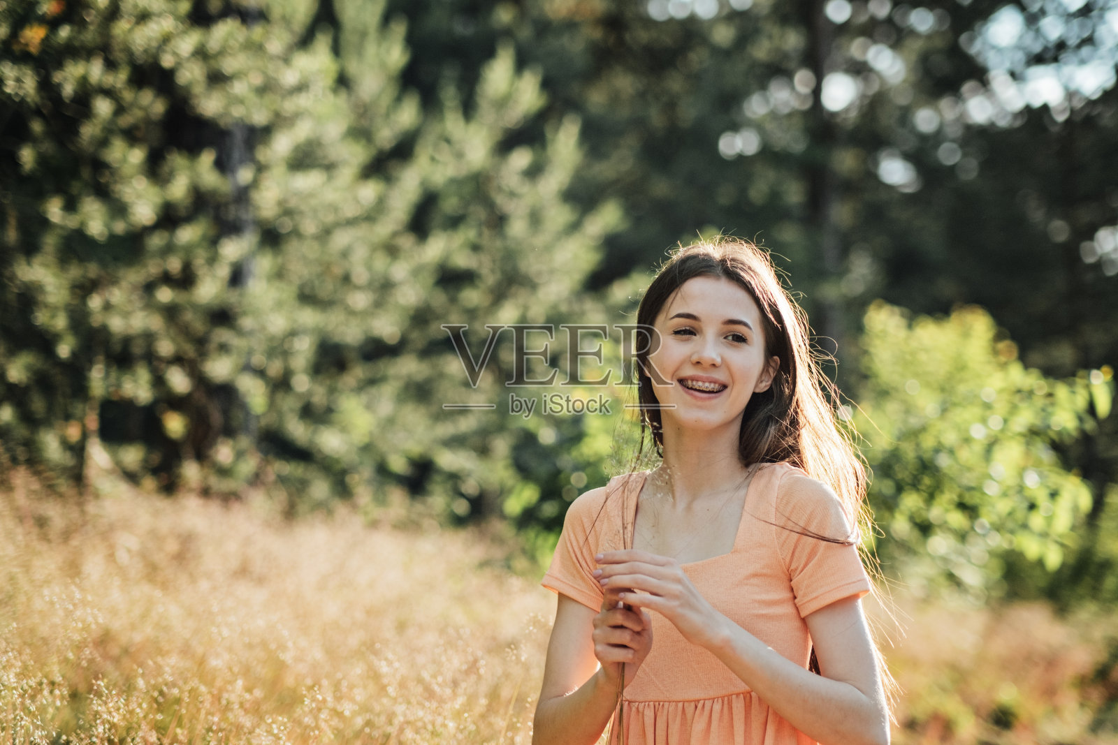 幸福、兴奋、喜悦、希望和灵感等积极情绪对幸福健康的生活至关重要。户外肖像的快乐微笑的年轻女子在自然背景照片摄影图片