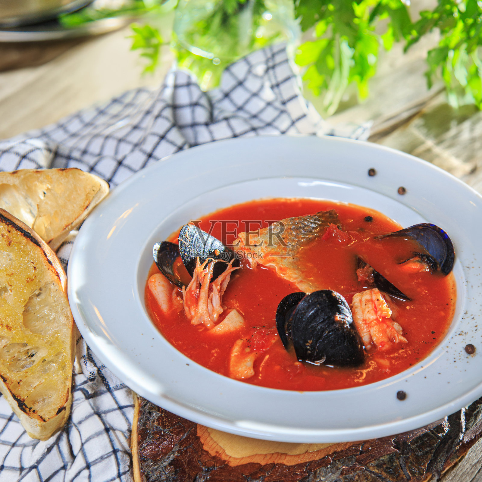 白盘子里的海鲜番茄汤配烤面包照片摄影图片