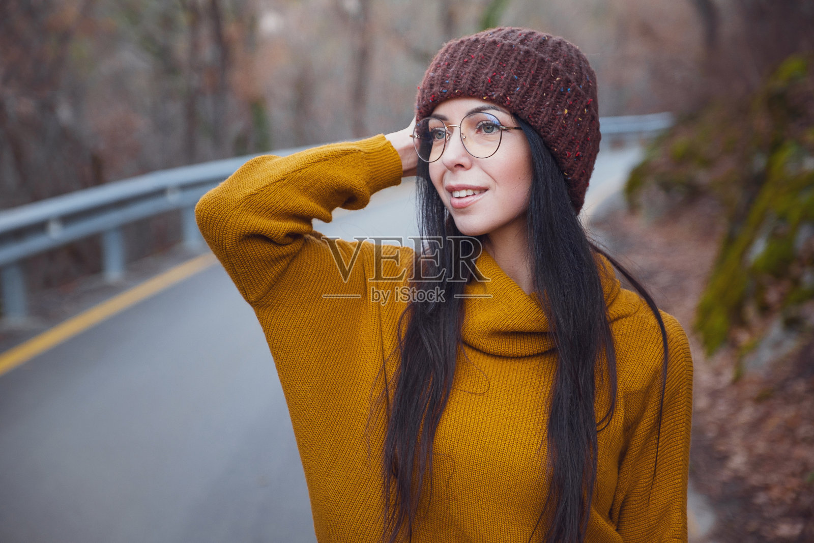 积极开朗的女人在公园或树林里享受秋天，穿着黄色的套头衫和帽子。照片摄影图片