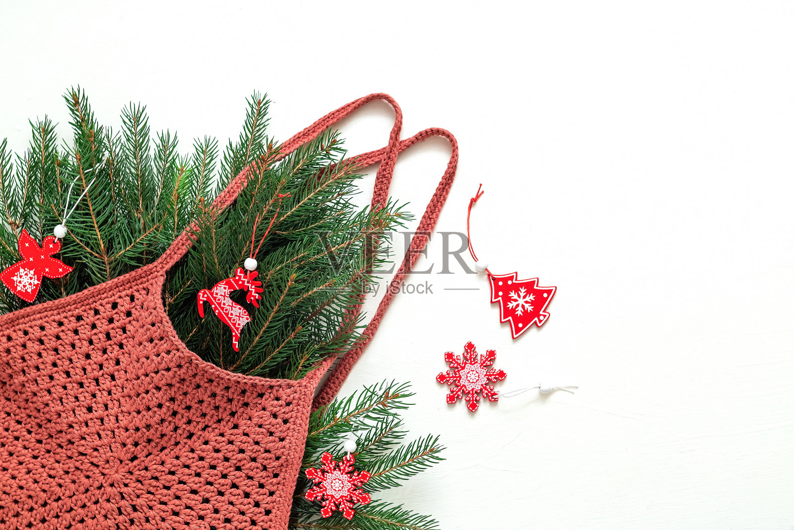 酒红色钩针生态袋六边形与冷杉树枝和圣诞木制玩具在一个白色的背景。副本的空间。照片摄影图片