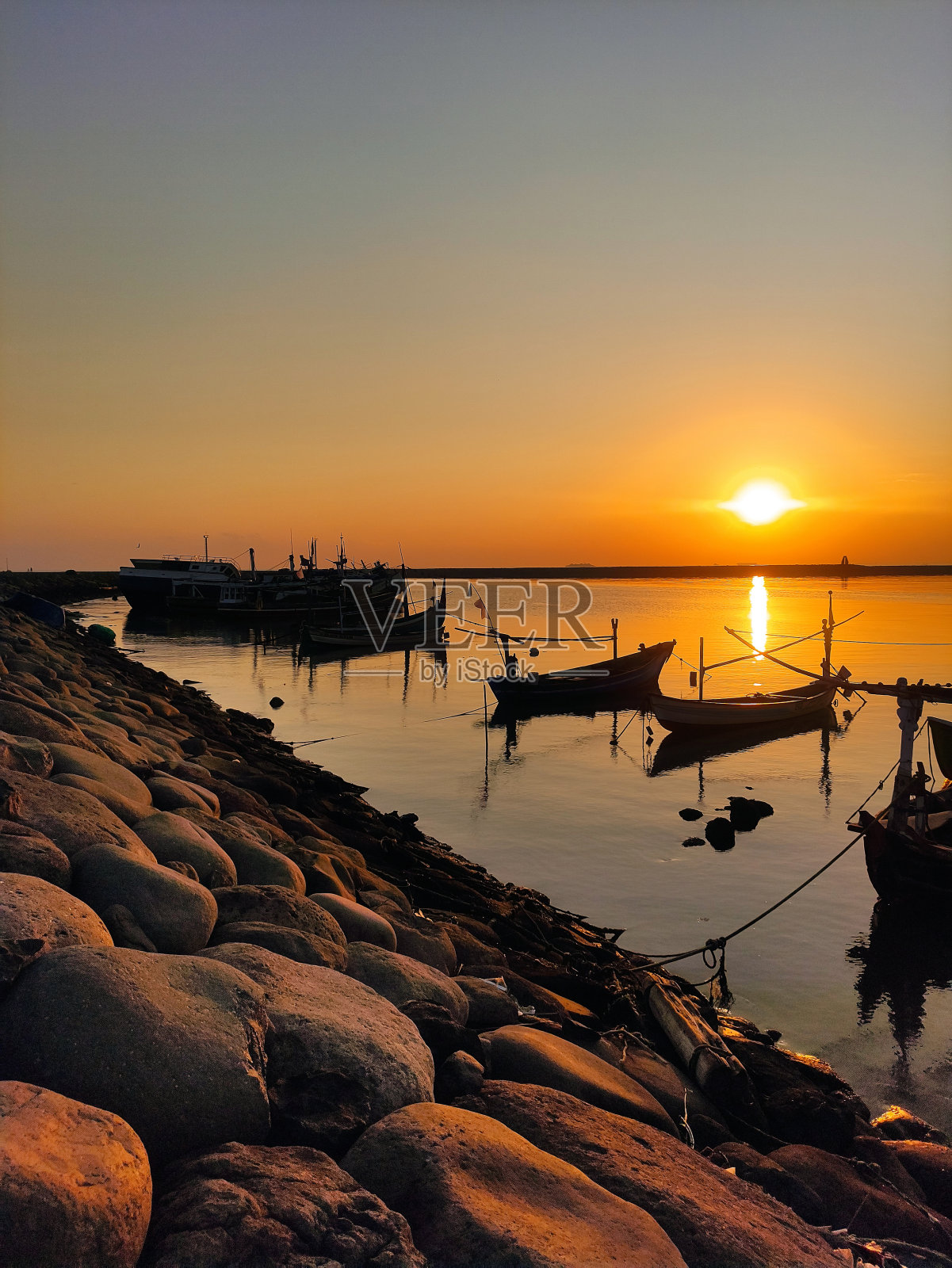 佩顿海滩上的夕阳和停泊在港口的渔船的剪影照片摄影图片
