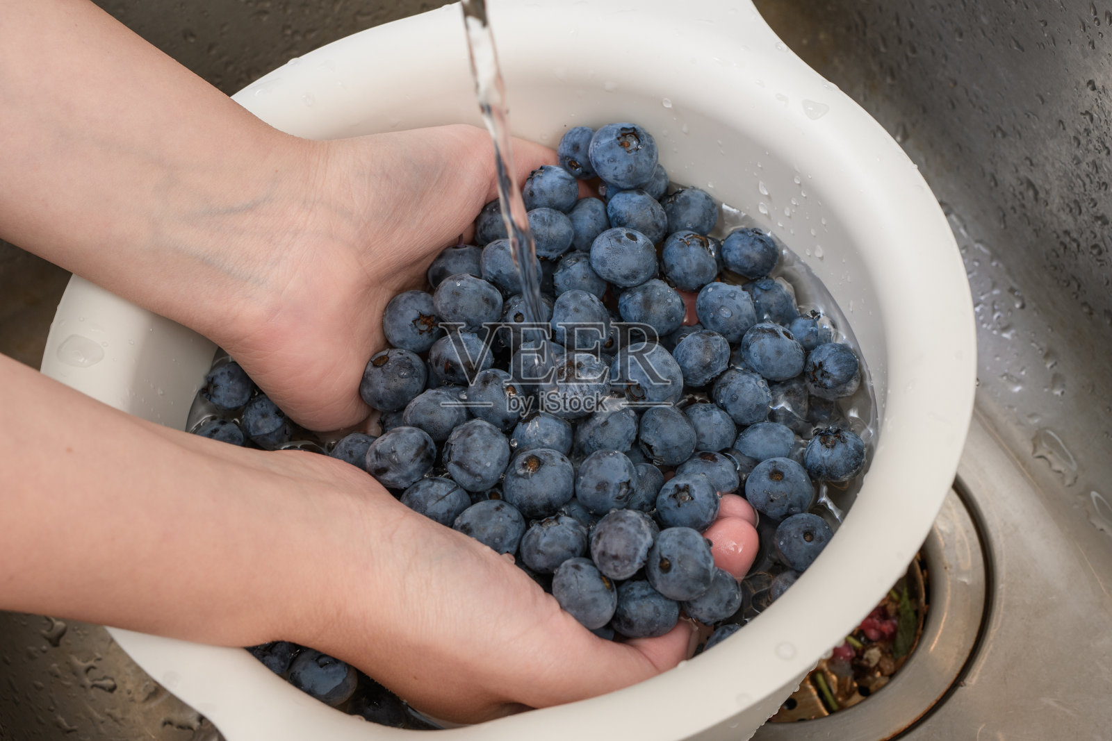 用滤嘴把浆果和水果洗净，拧开水龙头里的水照片摄影图片