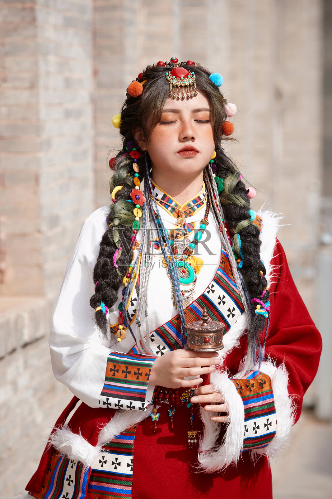 穿着藏族服装的女孩正在古城里拍照。照片摄影图片