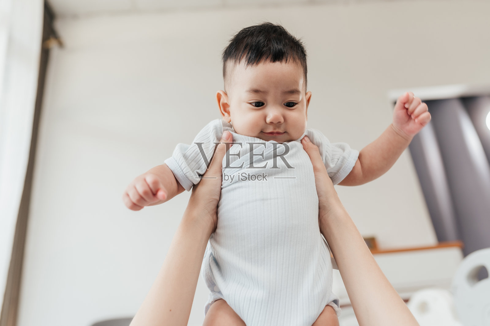 亚洲可爱的宝宝喜欢和父母一起玩。父母抱着小婴儿，举着孩子玩耍。个人观点。照片摄影图片