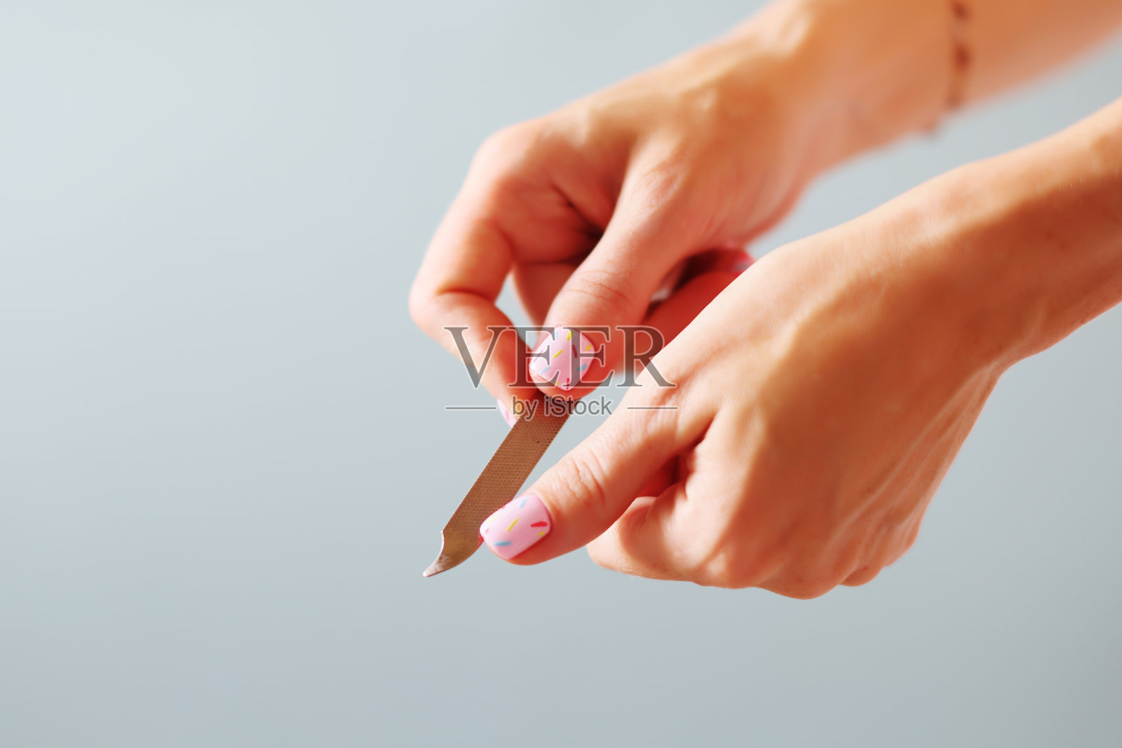 用蓝色背景的玻璃指甲锉手工锉指甲照片摄影图片