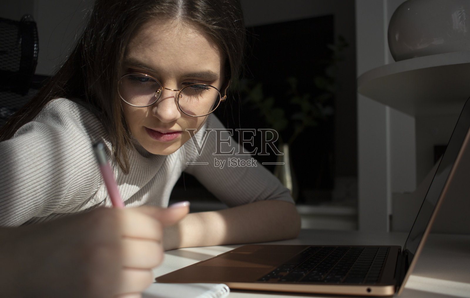 戴眼镜的年轻女孩在笔记本上写字照片摄影图片