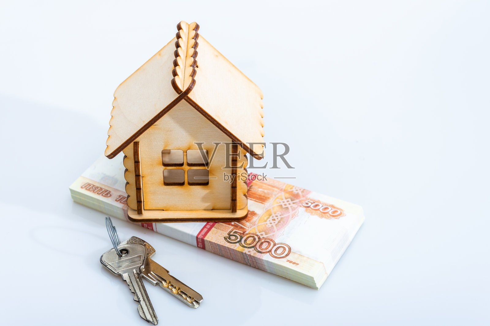 一间木屋，钥匙挂在一捆俄罗斯钞票上。白色背景。照片摄影图片