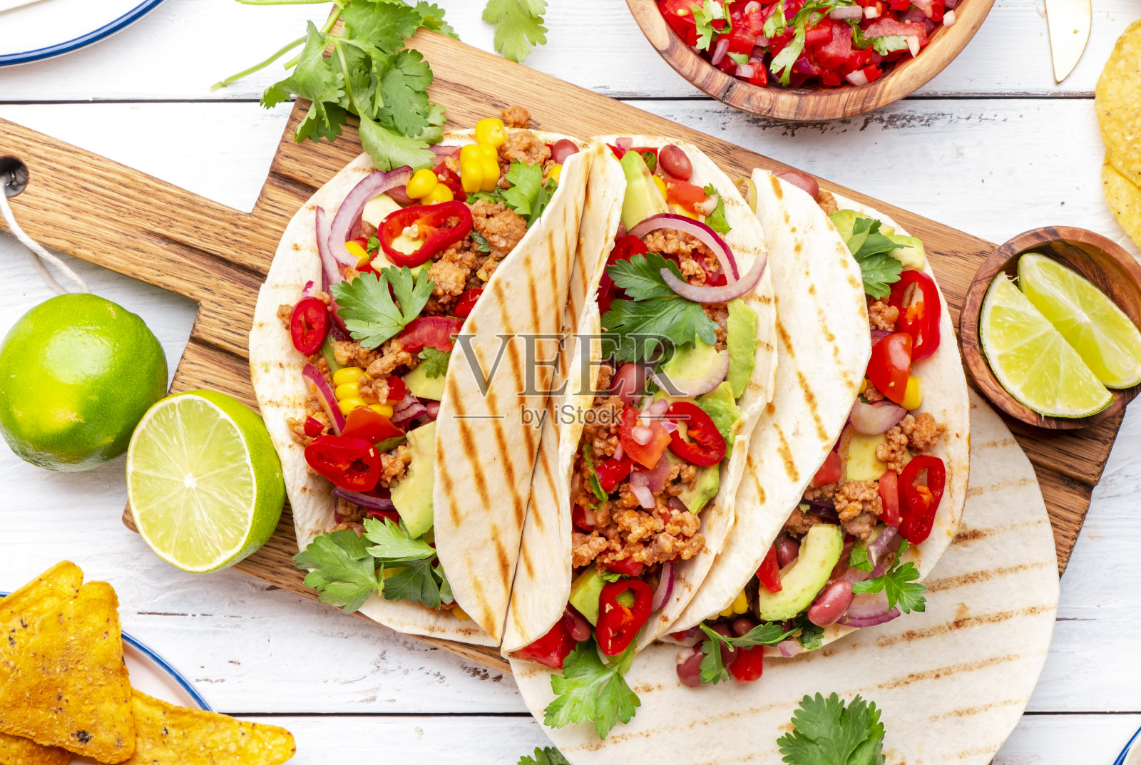 墨西哥菜。玉米饼上有牛肉、玉米、红豆、番茄莎莎酱和洋葱。白色桌面背景，俯视图照片摄影图片