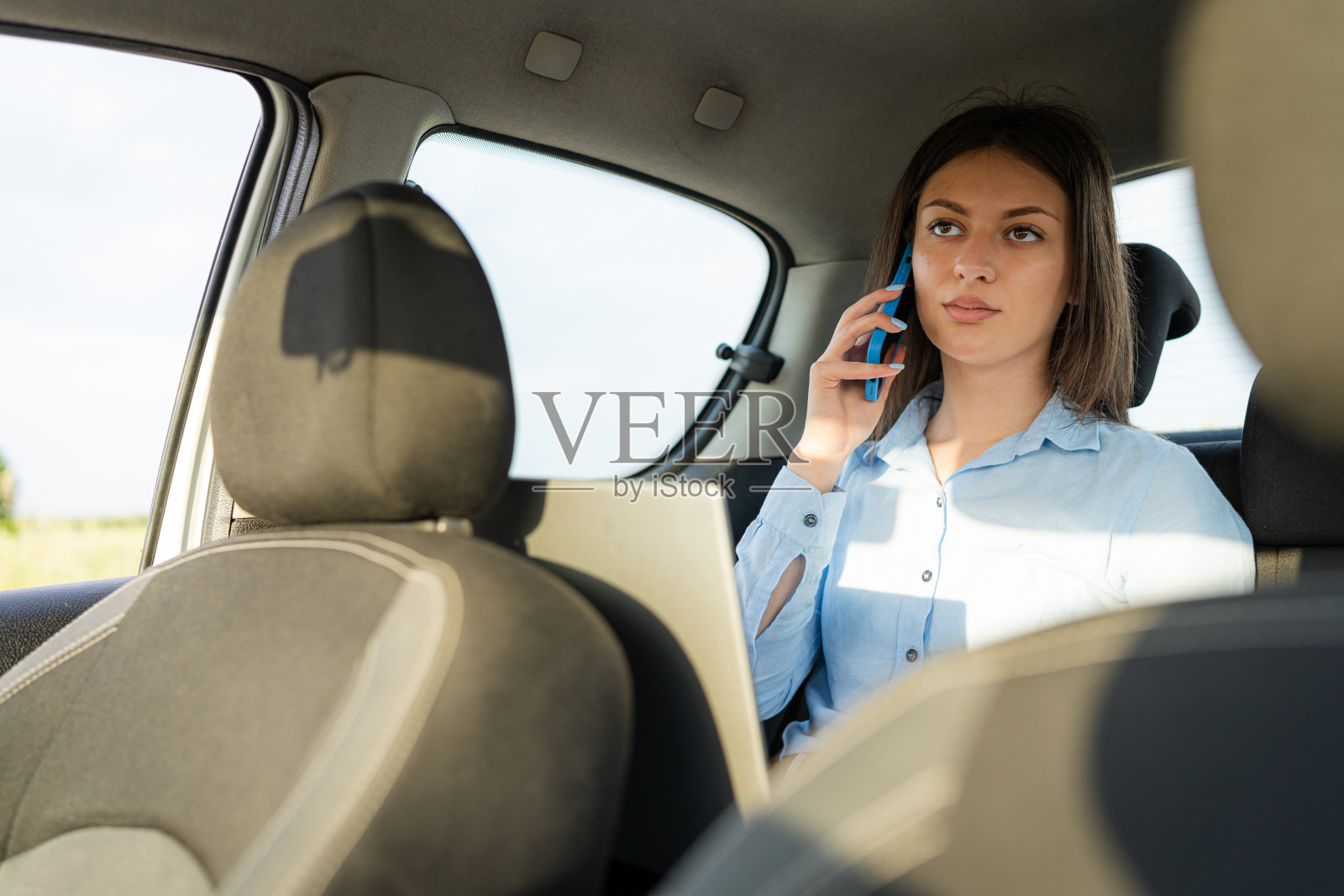 一名年轻女子坐在汽车后座上玩手机照片摄影图片