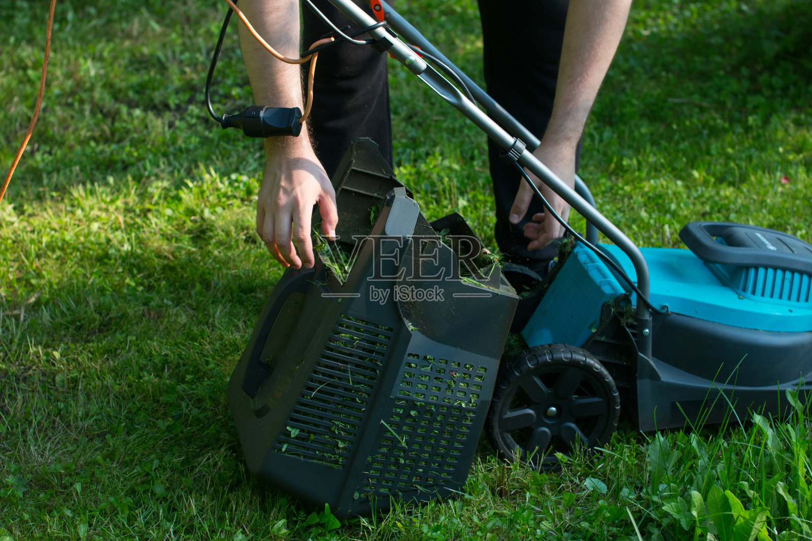 一个男人用割草机割草。割草机上青青的草地，草地上男人的断腿照片摄影图片