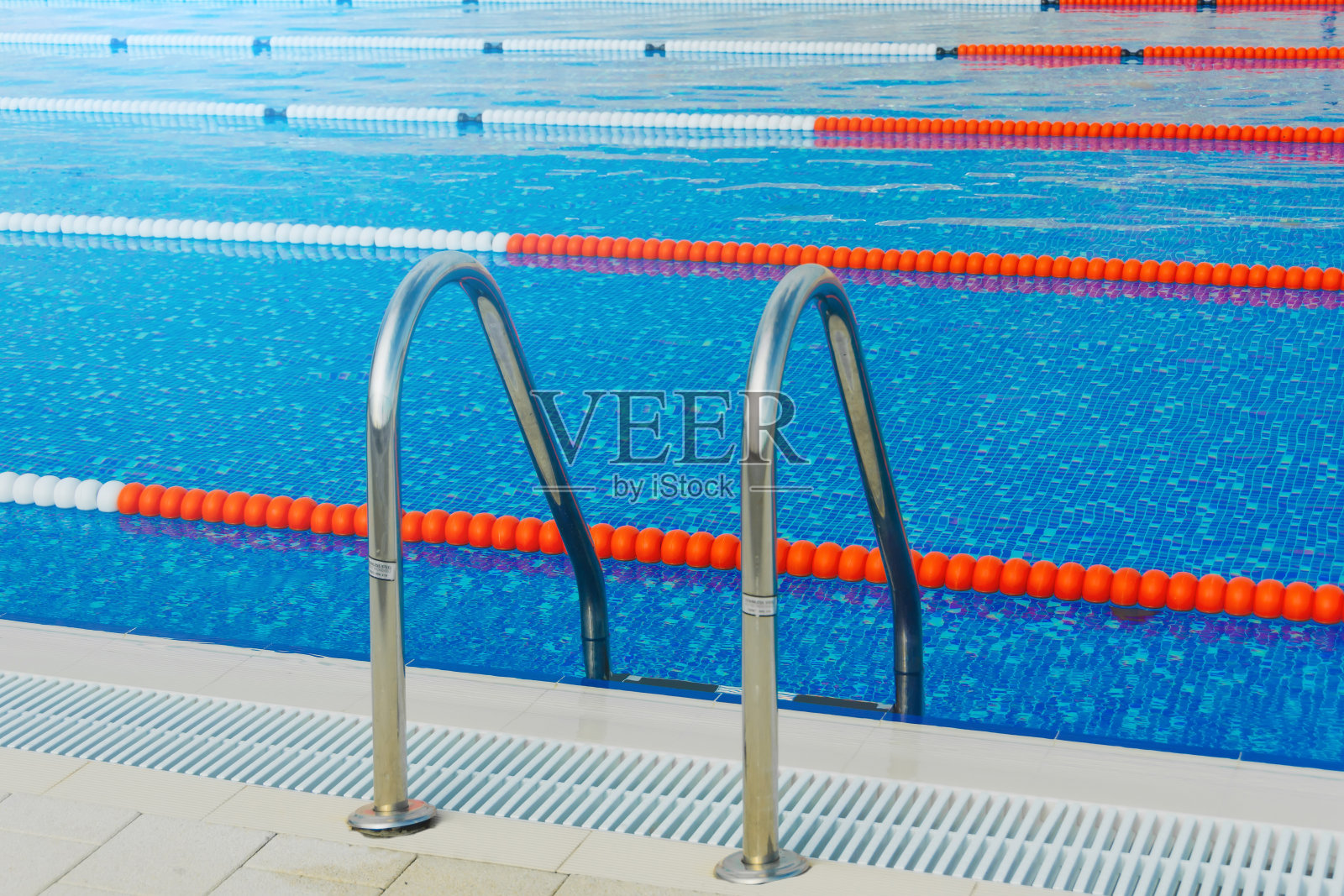 游泳池，有比赛和训练的分道泳道，有户外游泳和潜水的梯子，阳光明媚。照片摄影图片