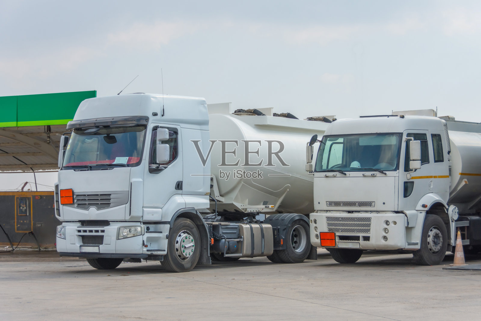 两辆运送燃料的卡车停在城市加油站。照片摄影图片