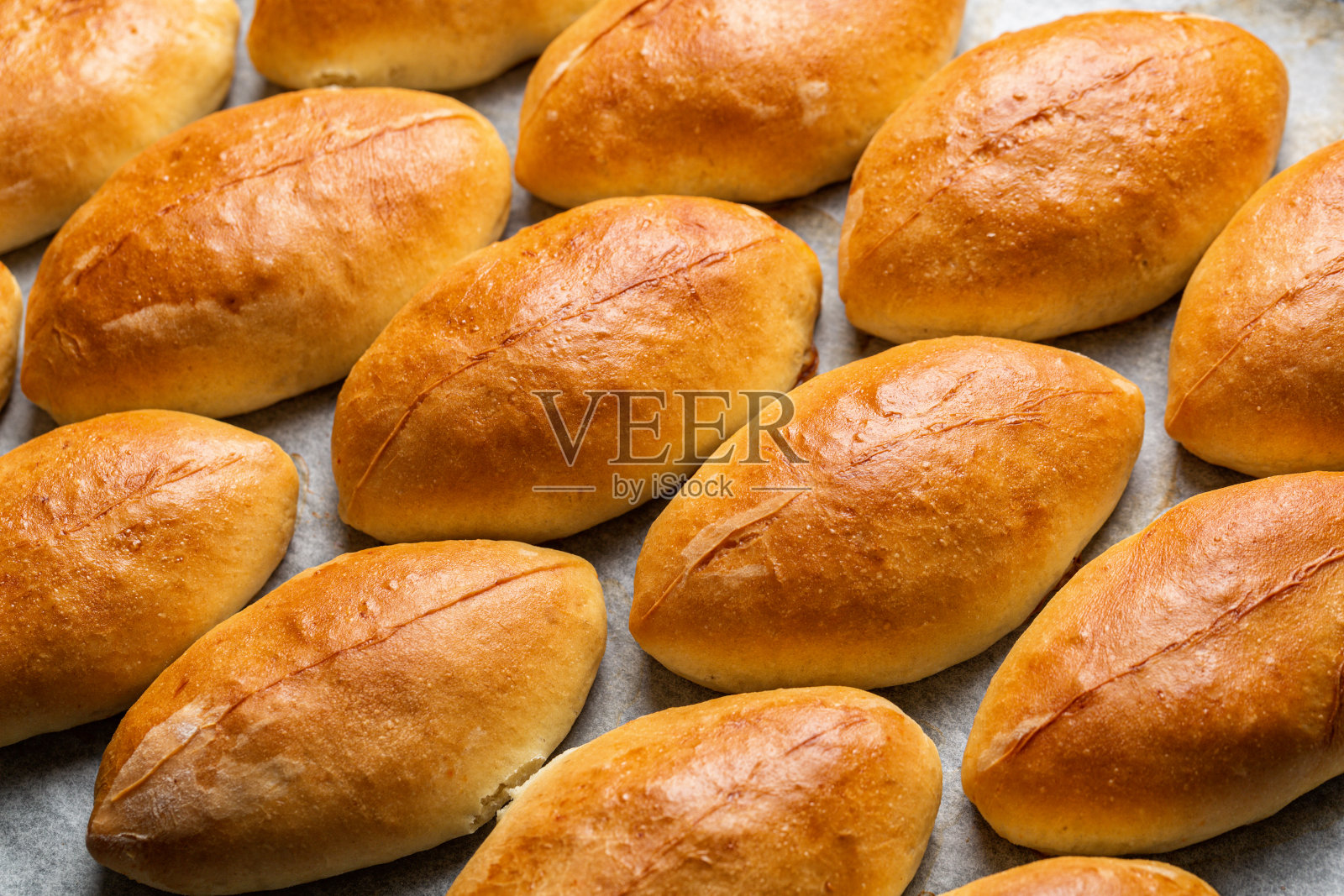 在烤盘上烤小馅饼。特写镜头。自制的船形酵母包，包里有卷心菜。东欧食物。照片摄影图片