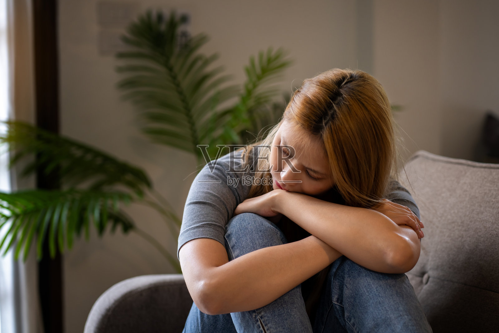 压力，焦虑和沮丧的女人独自坐在家里的沙发上照片摄影图片
