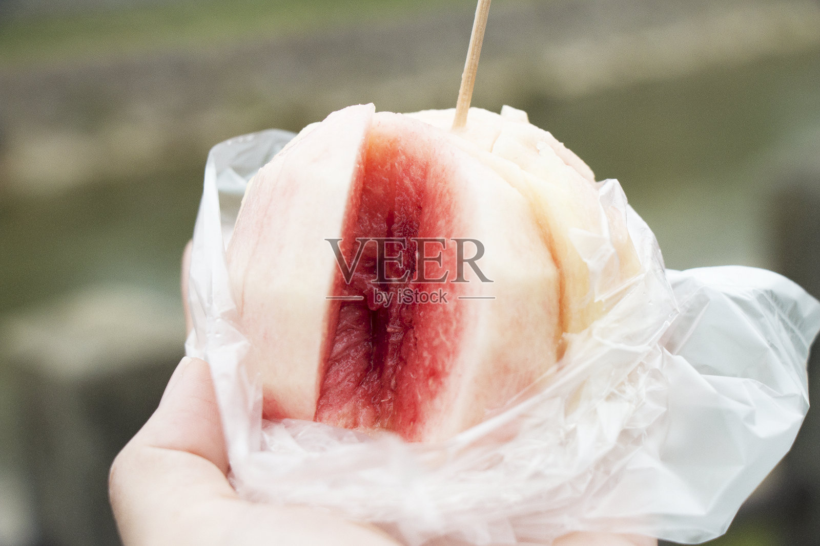 去桃子皮，把它们放在塑料袋里，拿在手里准备吃。照片摄影图片