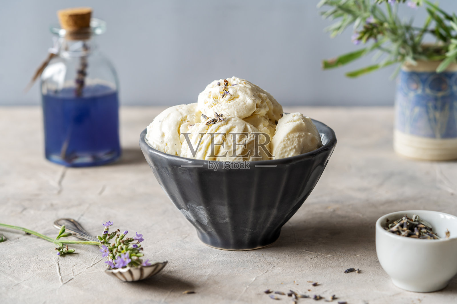 薰衣草冰淇淋放在一个灰色的碗里，配上薰衣草糖浆，薰衣草树枝插在陶瓷花瓶里，背景是灰色的混凝土照片摄影图片