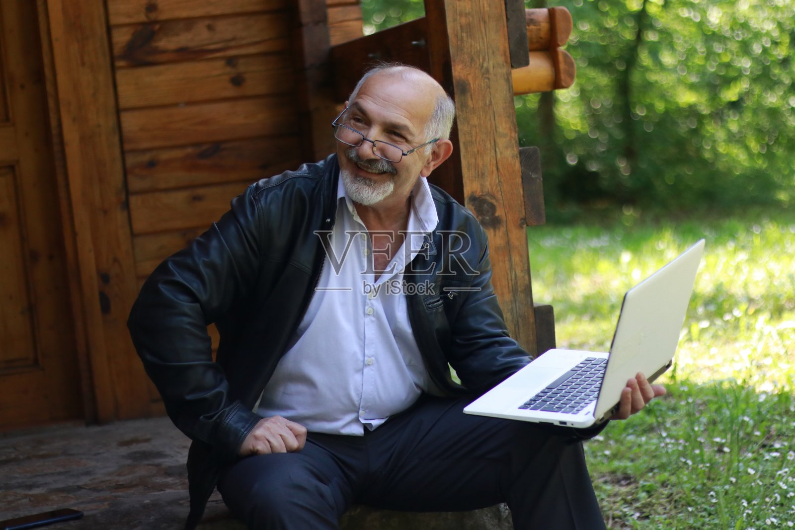 成熟的商人在笔记本电脑上工作。英俊成熟的商界领袖坐在大自然中照片摄影图片