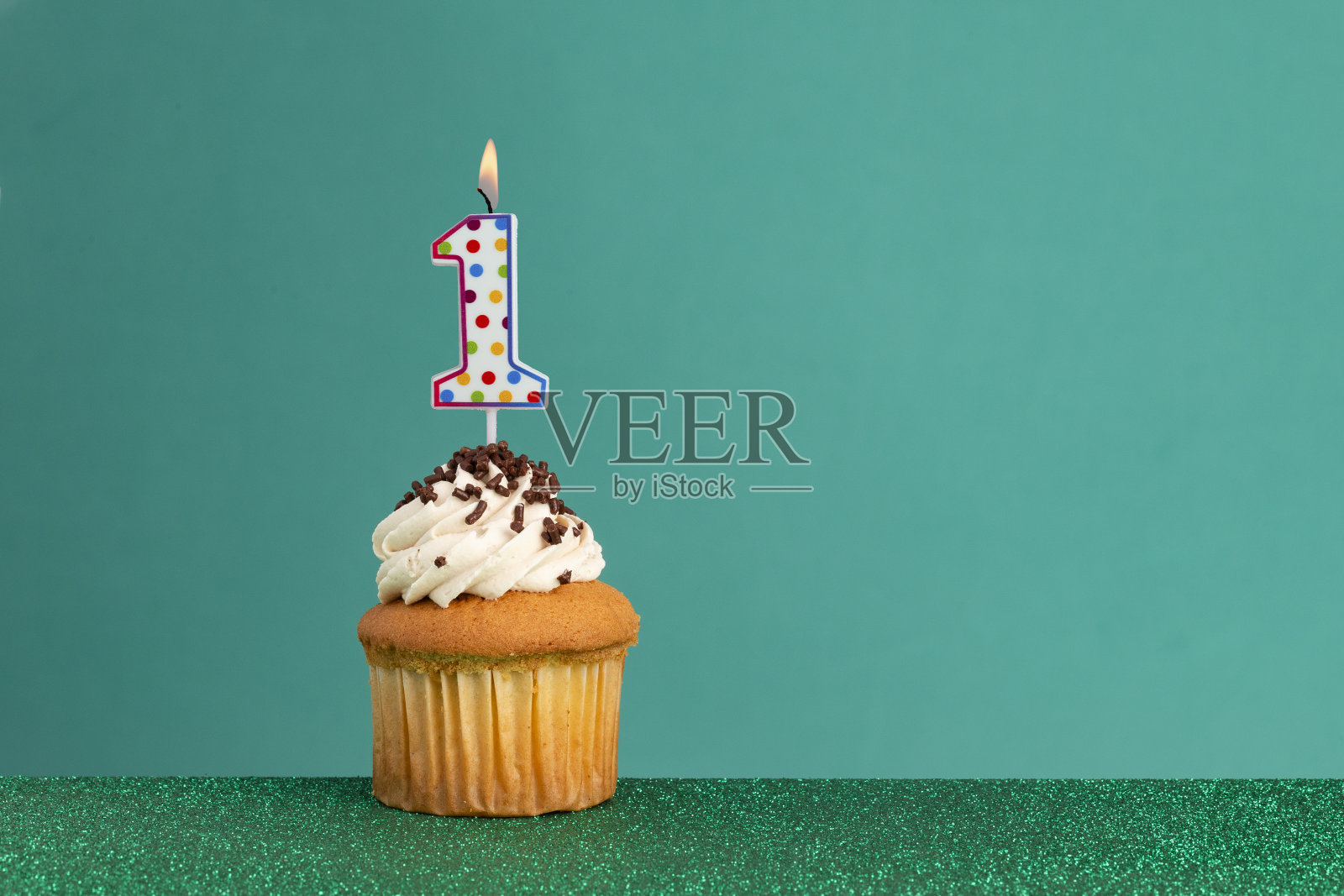 绿色背景上的生日蜡烛和生日纸杯蛋糕照片摄影图片