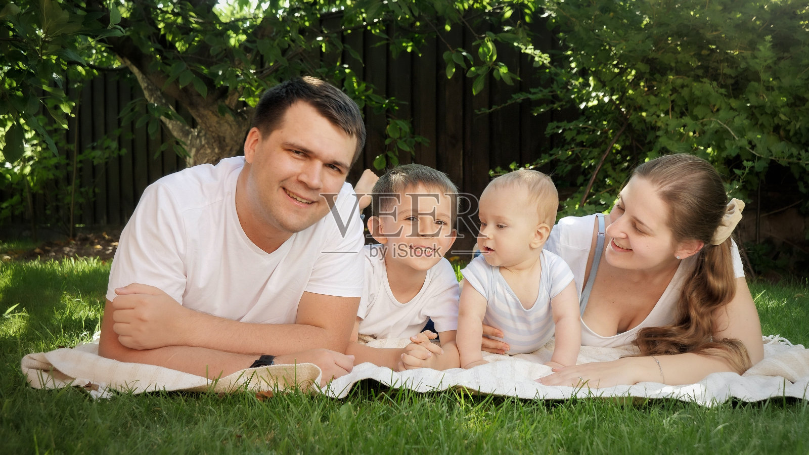 野餐时，一家人微笑着在公园的草地上放松照片摄影图片