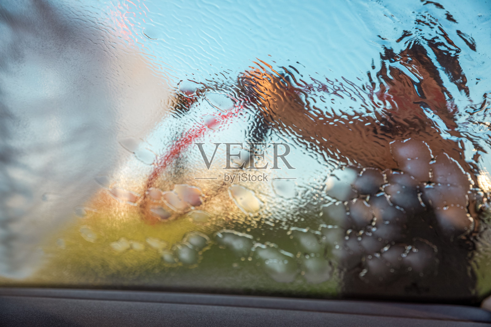 一名男子在户外自助洗车站洗车。从车内看照片摄影图片