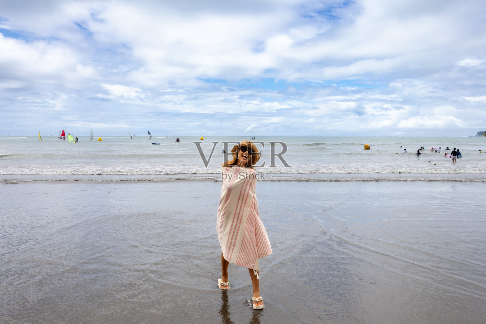 穿着毯子站在夏日沙滩上的快乐女人照片摄影图片