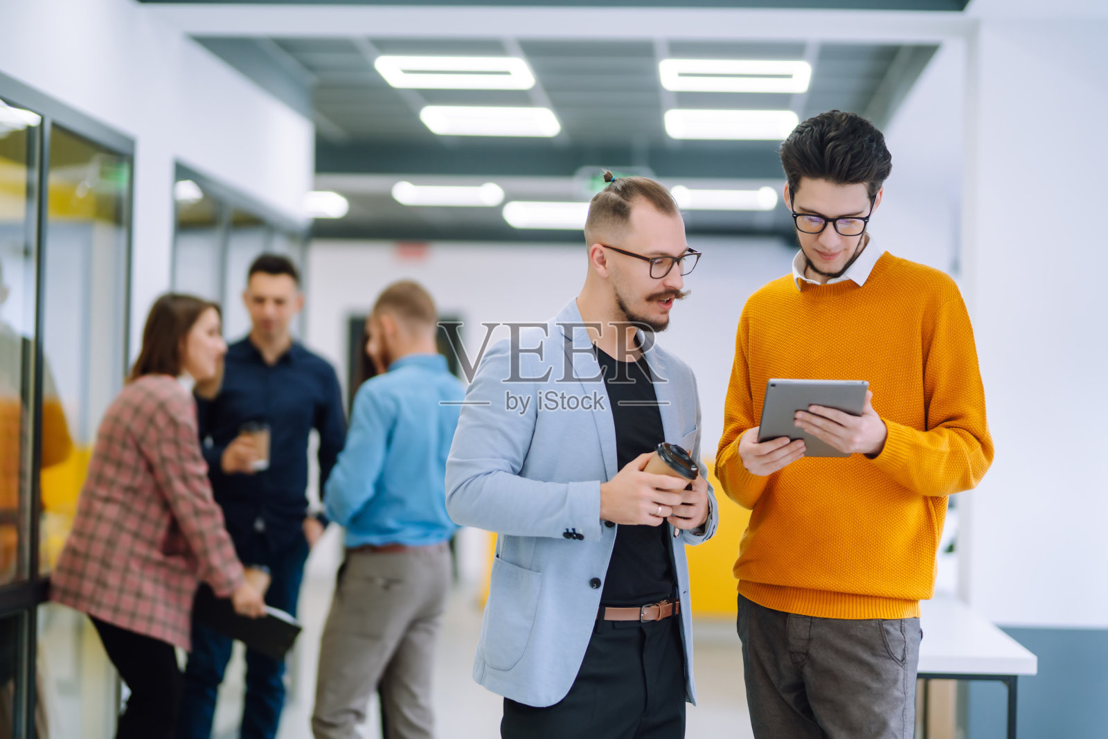 在现代办公室里一起工作的年轻人一起讨论工作问题。照片摄影图片