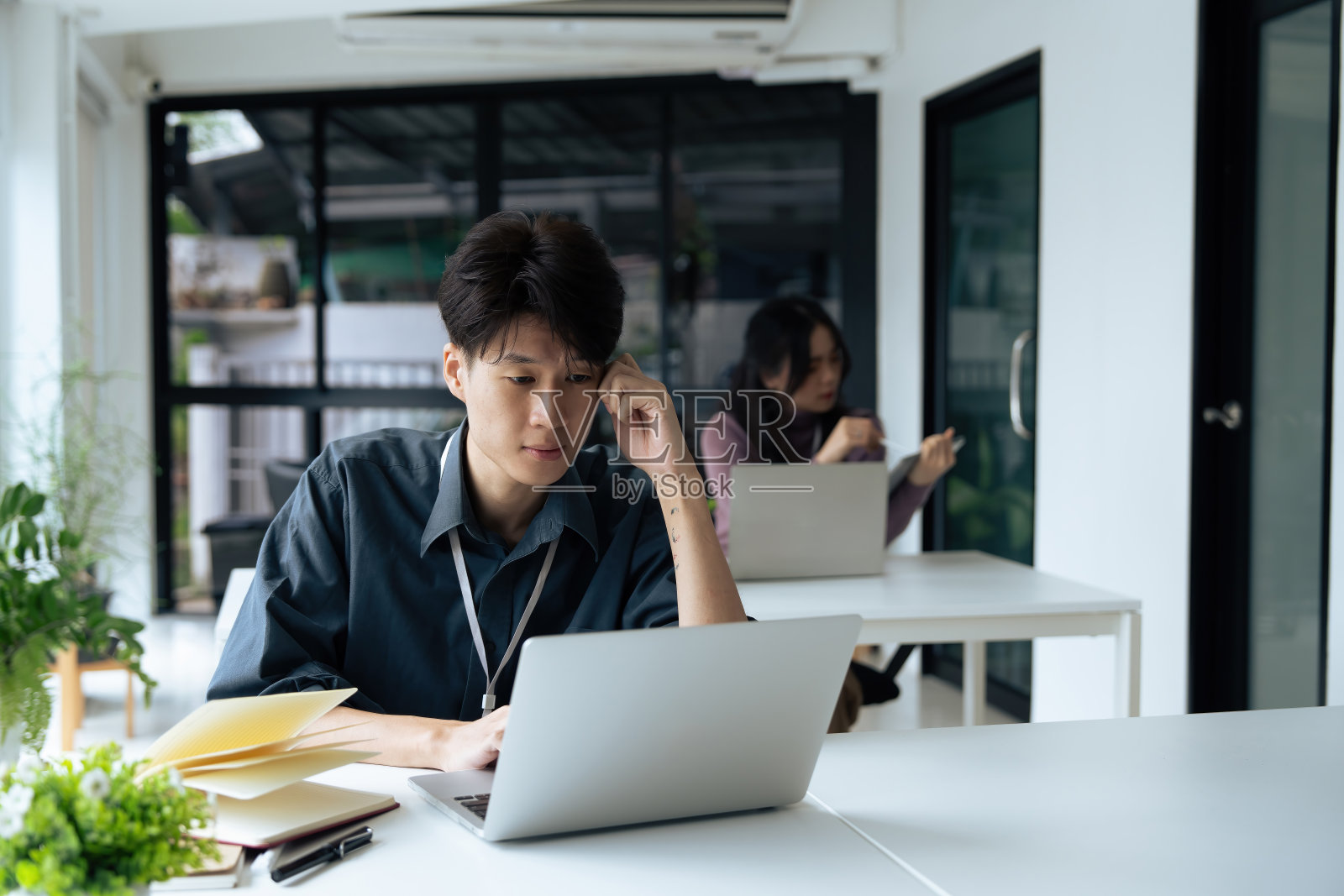 疲惫不堪的上班族坐在办公桌前思考，他揉着眼睛，感到筋疲力尽照片摄影图片