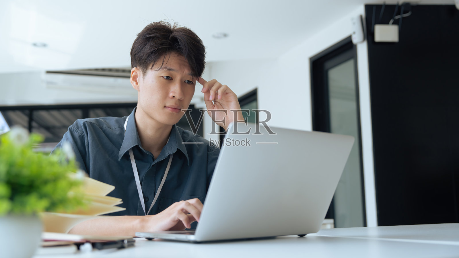 疲惫不堪的上班族坐在办公桌前思考，他揉着眼睛，感到筋疲力尽照片摄影图片