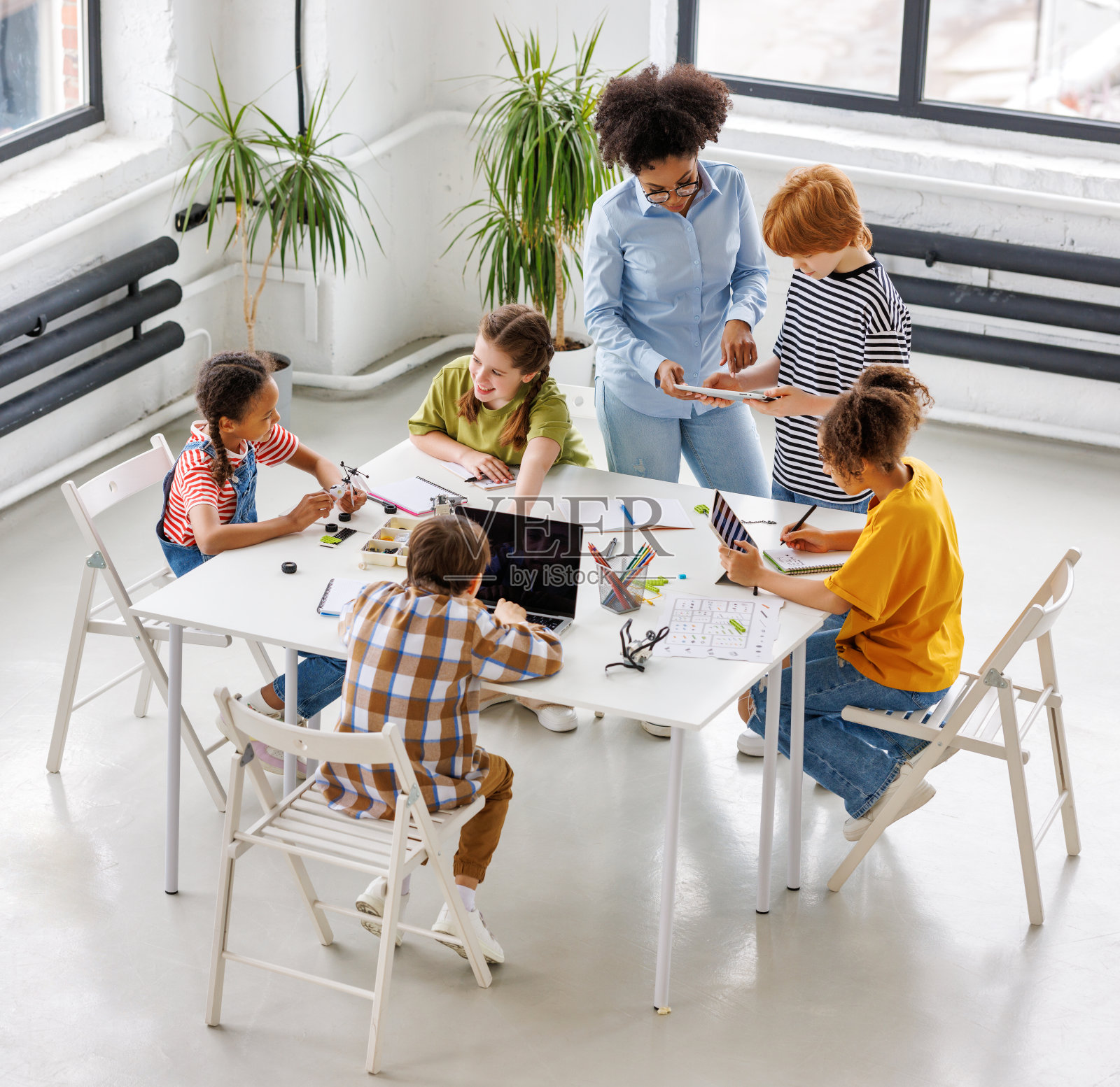 非裔美国教师微笑着检查学生在课堂上看平板电脑的作业照片摄影图片